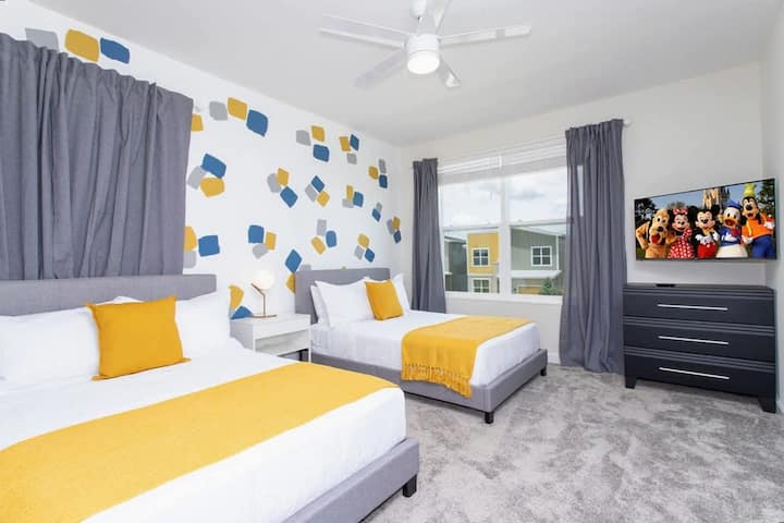 Oddýchnite si v tejto živej spálni s dvoma plyšovými posteľami v plnej veľkosti, veselými žltými akcentmi a televízorom pre dokonalý rodinný oddych.