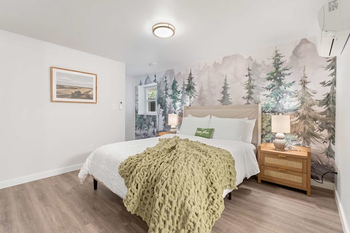 Pokojný výlet s nástennou maľbou lesa a zeleným vankúšom s nápisom „Happy Place“.