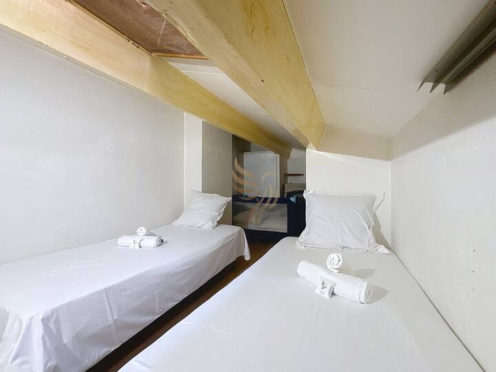 Спалня на тавана с красива естествена светлина и две единични легла.