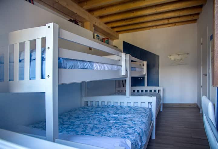 Спална соба со кревети на два ката каде што долните кревети се брачни, а горните единечни (за деца)