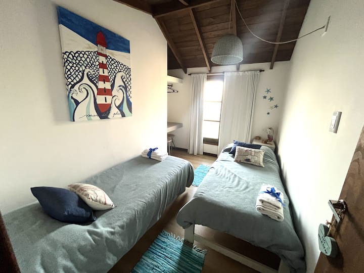 Секундарна спална соба на високо ниво, со два единечни кревета од 0,70 x 1,90. Светл простор, високи тавани и морски детали кои ве покануваат да се одморите мирно и стилски.