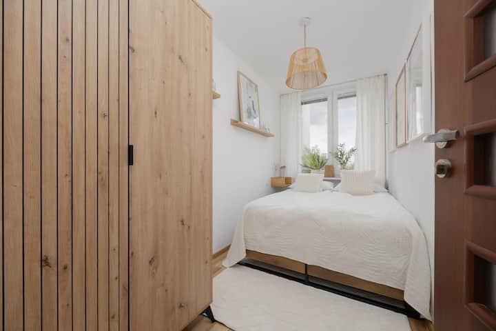  Dizajn i ngrohtë i dhomës së gjumit me tekstura druri dhe shtroja të rehatshme.