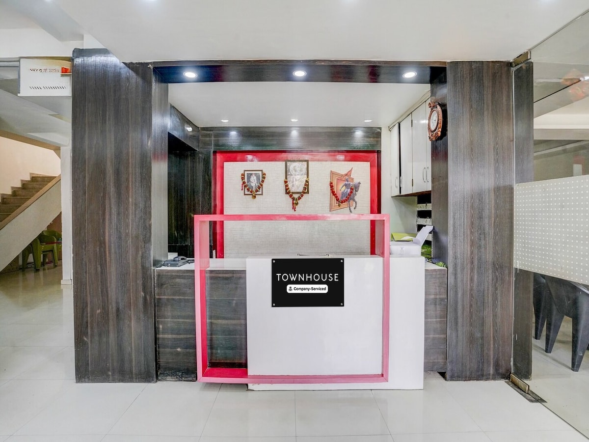 The reception area features a modern front desk with a white finish, complemented by a vibrant pink accent. Wall decorations include framed art pieces. The space is well-lit, showcasing sleek flooring and surrounding seating options, providing a welcoming entry point for guests.