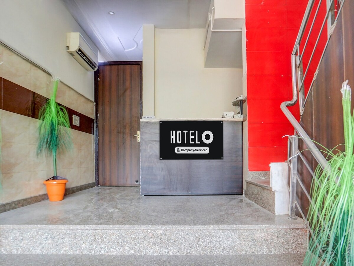 The entrance area features a reception desk situated on a granite floor, with a wooden door leading to guest access. A potted plant adds a touch of greenery, while the walls display a subtle mix of colors, providing a welcoming first impression.