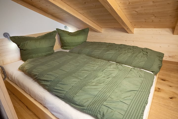 דירה קטנה עם מיטה זוגית מתחת לגג ונוף אלפיני