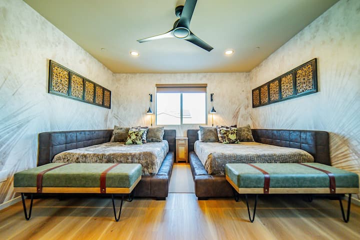 SALA OLIVE. Segundo piso. Dos camas dobles extragrandes, colchones de espuma viscoelástica, lámparas de noche, estaciones de carga, televisor inteligente, ropa de cama hipoalergénica, almohadas mullidas, opciones de soporte para el cuello y cortinas opacas para un sueño reparador.