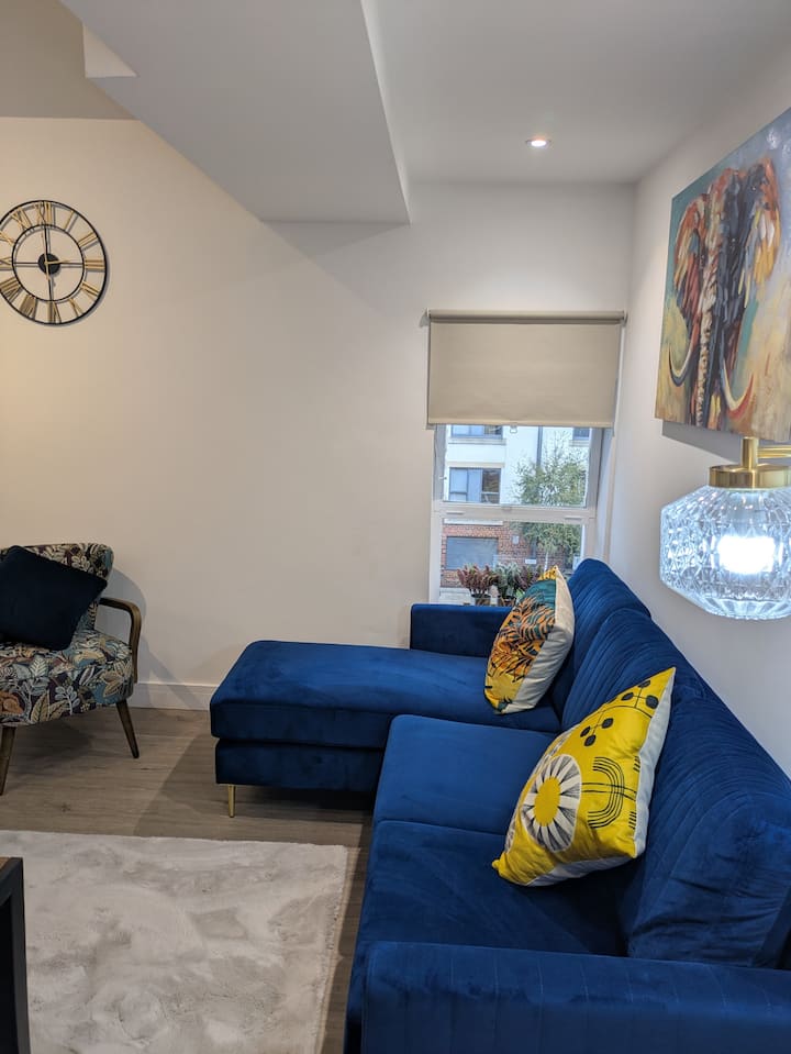 Apartamento 24 – Sala de estar con vista a la calle tranquila.  Sala de estar luminosa de diseño abierto con TV inteligente, espacio para comer y conexión Wi-Fi rápida, ideal para relajarse o trabajar a distancia.