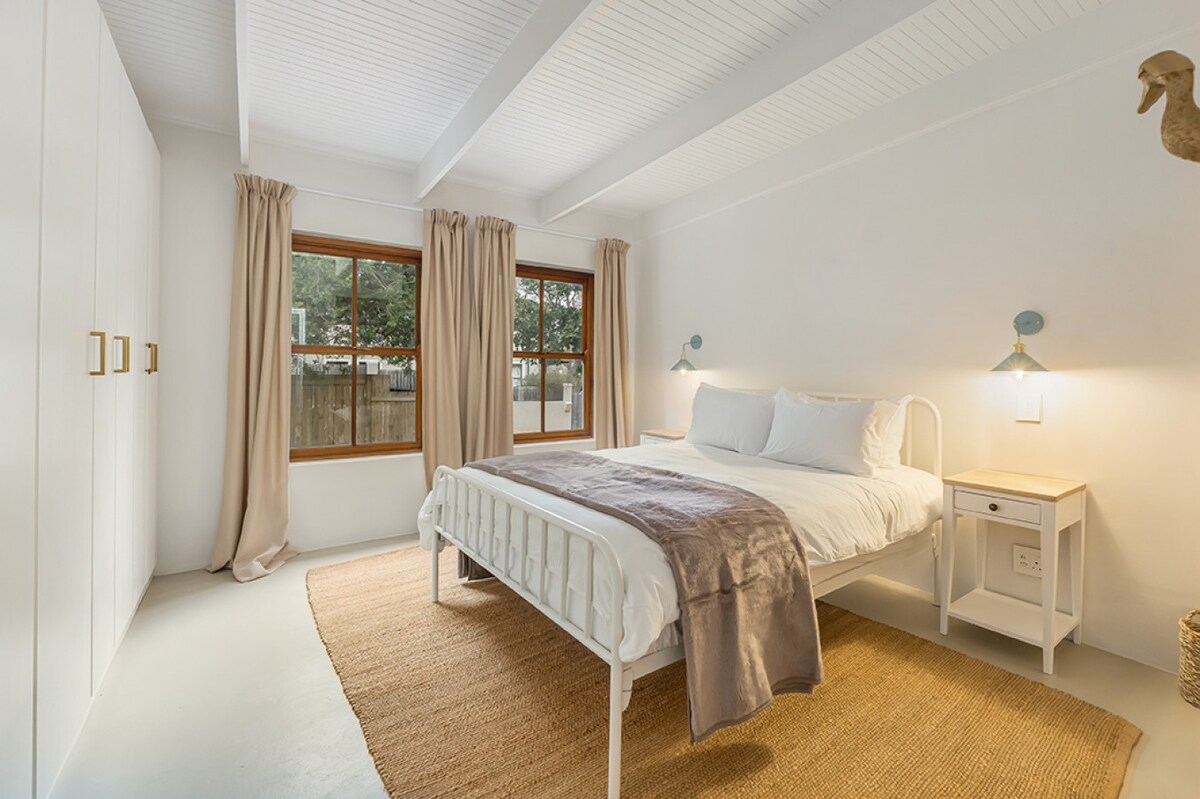 Een serene slaapkamer met zachte tinten en natuurlijk licht, een rustig toevluchtsoord om te ontspannen en op te laden.