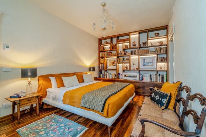  ✨ Päämakuuhuone: Rauhallinen retriitti, jossa on king-vuode, designer-lakanoita ja kirjahylly, jossa on kirjoja ja taidetta. Mukautettu Murano-valaistus ja lämpimät sävyt luovat täydellisen tilan levolle ja inspiraatiolle.