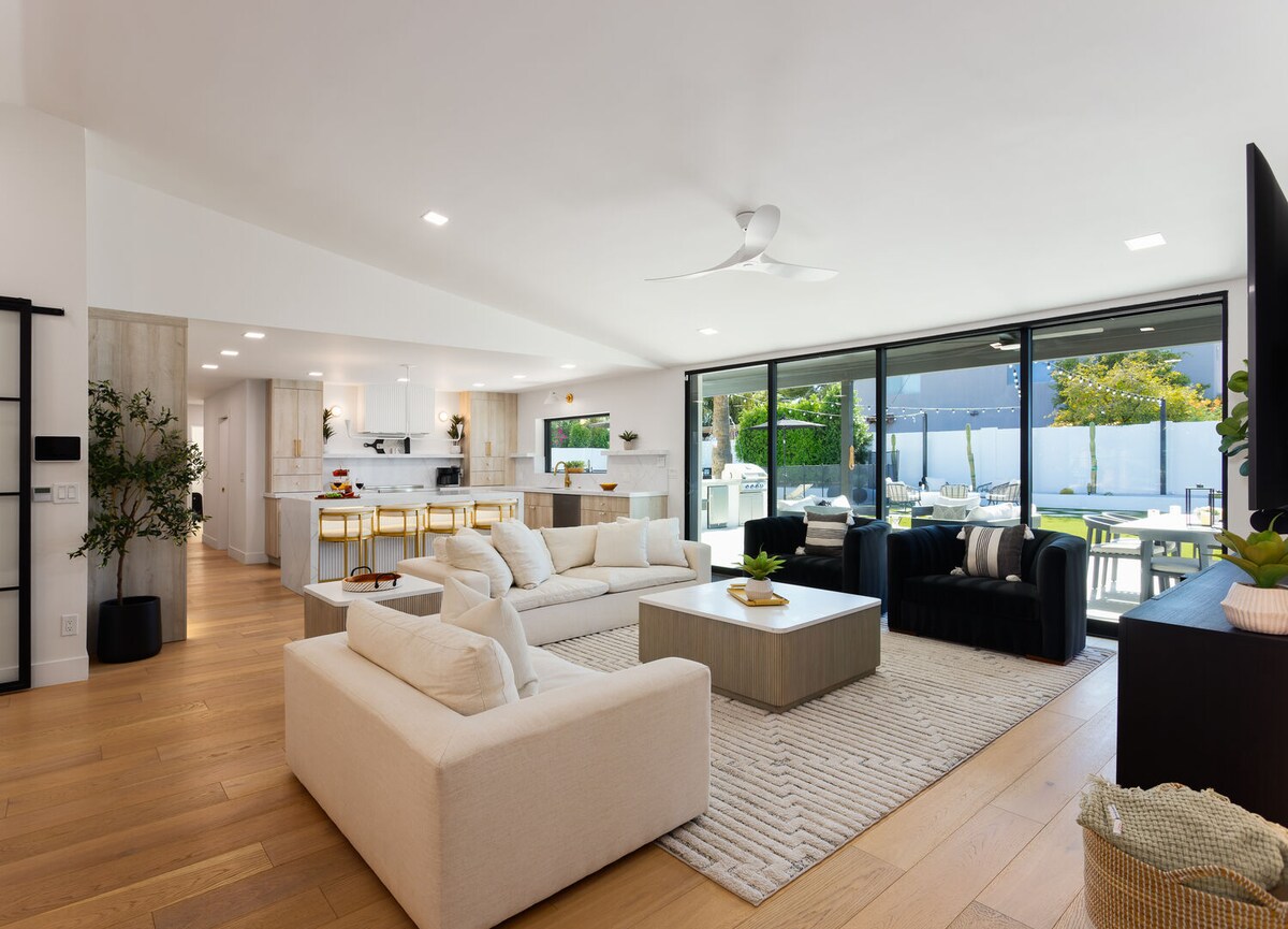 Bright open floor living space, designer furnishings, smart TV, and large sliding doors leading to the private resort-style backyard.