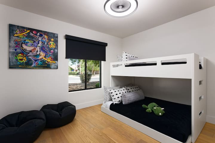 Tercer dormitorio con 1 cama individual sobre 1 cama completa (estilo litera), materiales de lectura para niños y espacio en el armario.