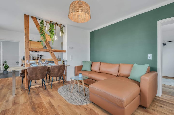 Sala de estar con un acogedor sofá de cuero y una pared de color verde salvia suave.