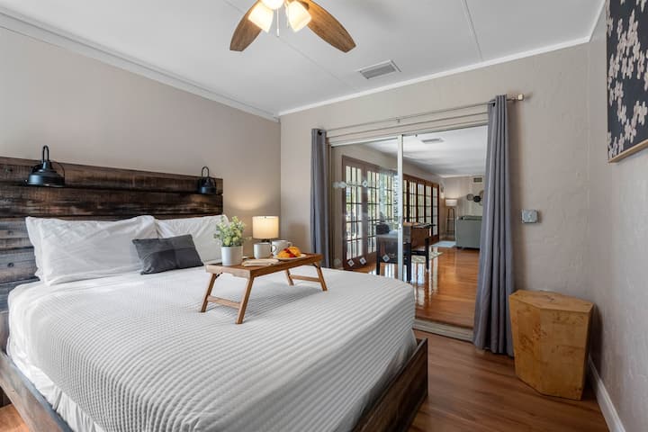 Táto spálňa ponúka útulné a príjemné útočisko s rustikálnym dreveným rámom postele, mäkkým osvetlením a upokojujúcimi neutrálnymi tónmi.