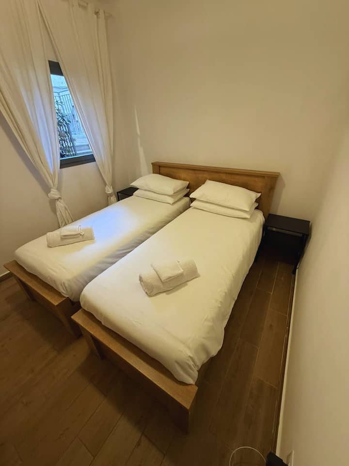 غرفة نوم مريحة مع سريرين مفردين وإضاءة ناعمة. 