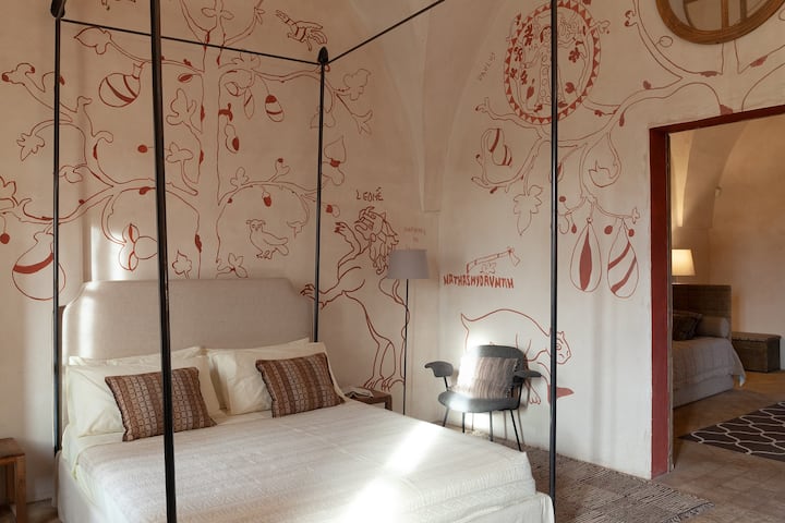 Dhoma e gjumit me krevat dopio dhe afresket e saj të kuqe.