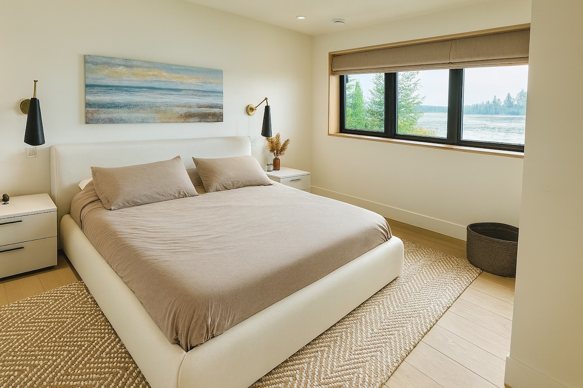 Light-filled bedroom with queen bed and calming water-inspired artwork.