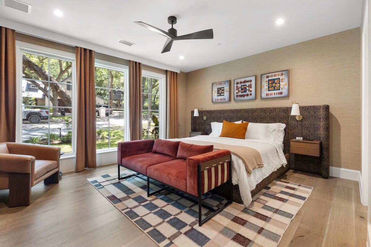 A refined retreat featuring a king bed with Ralph Lauren-inspired design, layered textures, and bold accents. Floor-to-ceiling windows frame natural light, while curated art and rich furnishings create a balance of comfort and sophistication.