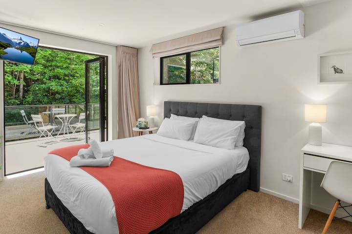 Spálňa 2: hlavná spálňa s vlastnou kúpeľňou a dverami na terasu. Výhľad na les a potok z terasy. Manželská posteľ, televízor so službou Netflix, klimatizácia/tepelné čerpadlo, šatníková skriňa, písací stôl a stolička, v prípade potreby k dispozícii detská postieľka