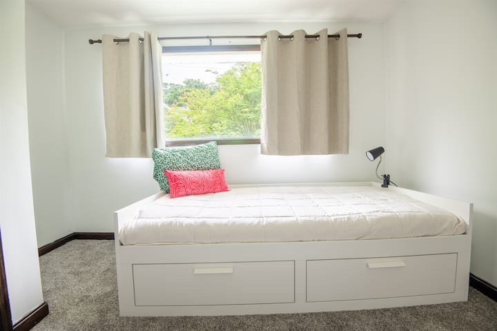 Спалня с две единични легла с голям прозорец – чудесна за самостоятелни гости или деца, с естествена светлина и меко легло.