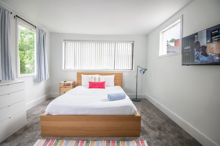 Слънчева спалня с телевизор – Отпуснете се в тази просторна спалня с голямо легло, ъглови прозорци и телевизор с плосък екран.