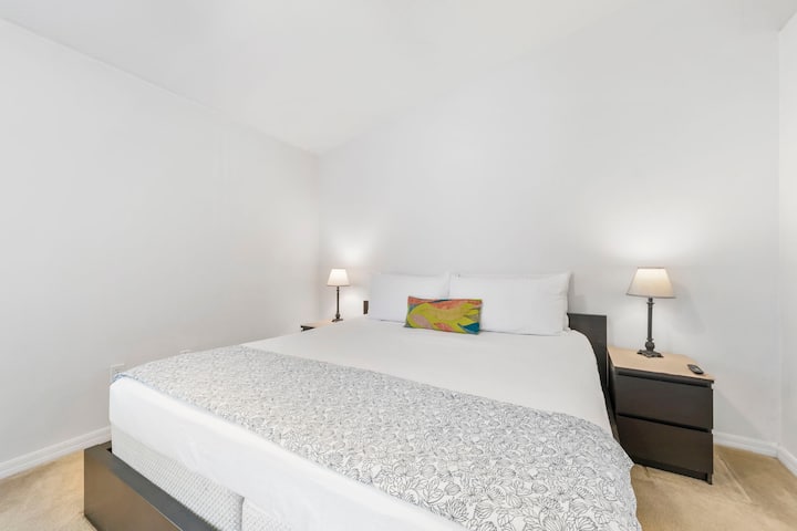 Приканващ основен апартамент с двойно легло, вентилатор на тавана, телевизор с плосък екран и самостоятелна баня, предлагащ просторно и спокойно място за почивка в края на деня.