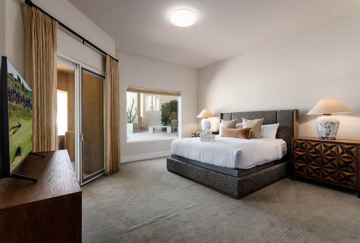 غرفة نوم ثالثة تضم سرير كينج وتلفزيون ذكي وخزانة ملابس وخزانة ملابس كبيرة وحمام داخلي وإمكانية الوصول إلى الفناء الأمامي.