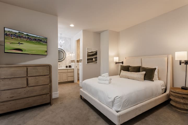 غرفة نوم ثانية تضم سريرًا بحجم كوين وتلفزيونًا ذكيًا وخزانة ملابس وخزانة ملابس وحمامًا داخليًا وإمكانية الوصول إلى الفناء الخلفي.