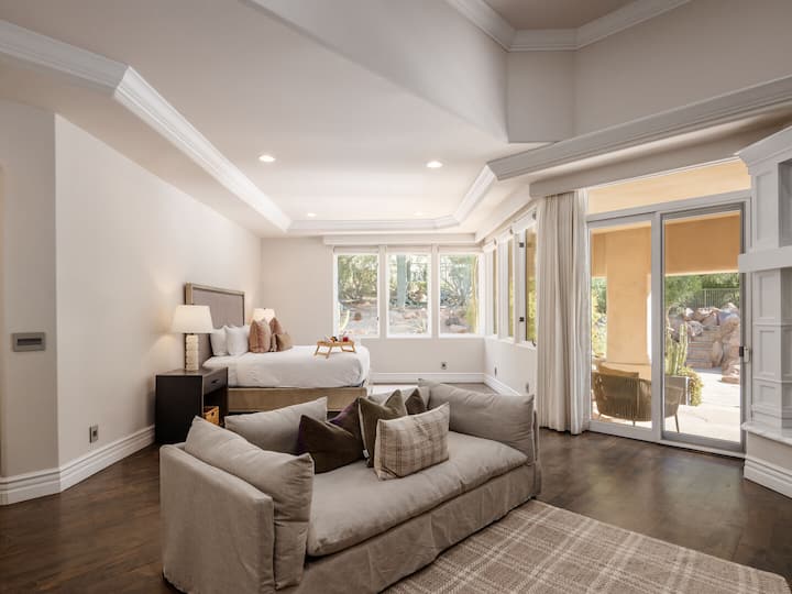 غرفة نوم رئيسية تضم سرير كينج ومفروشات مريحة وتلفزيون ذكي ومدفأة كهربائية وخزانة ملابس كبيرة وحمام داخلي وإمكانية الوصول إلى الفناء الخلفي.