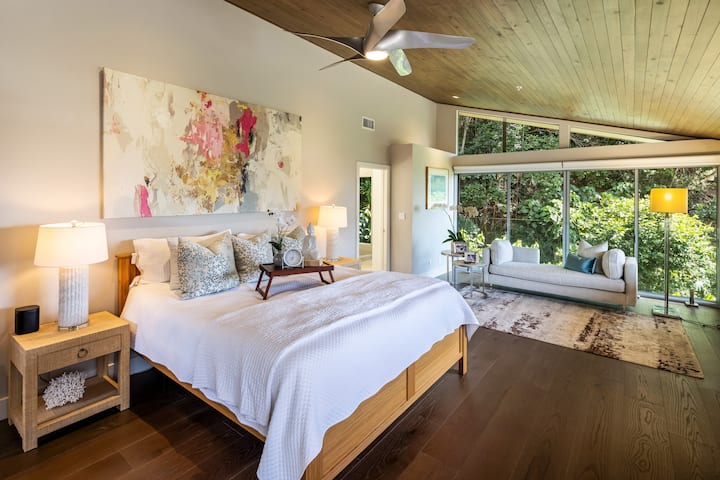 Suite principal con cama tamaño king, techo abovedado y vistas al exuberante jardín: tu escapada privada a la montaña.