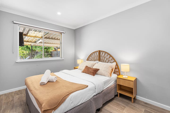 Cama cómoda con cabecero de ratán elegante y hermosas vistas al jardín. 