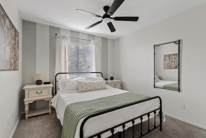 Bedroom 3:  This room features a cozy queen bed framed by a striped accent wall and soft décor, creating a calm retreat filled with natural light.