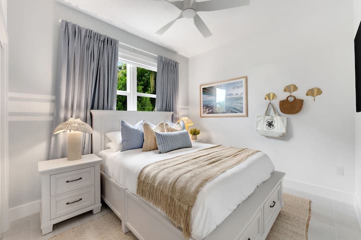 Pokojná spálňa v pobrežnom štýle s manželskou posteľou, zásuvkami a slnečným svetlom