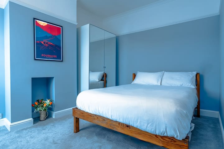 - Camera da letto con pareti dipinte di blu in legno e opere d'arte moderne - Biancheria fresca e guardaroba a specchio creano uno spazio luminoso e tranquillo - Rifugio rilassante perfetto per rilassarsi dopo aver esplorato la città 