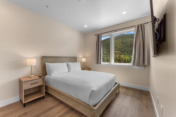 El dormitorio principal de la planta principal incluye una cama tamaño queen, TV inteligente montada y baño privado. 