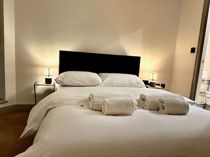 Segundo dormitorio con una cómoda cama doble, lámparas de noche y sábanas frescas. Perfecto para parejas, amigos o familias que se alojen en este departamento céntrico de York.