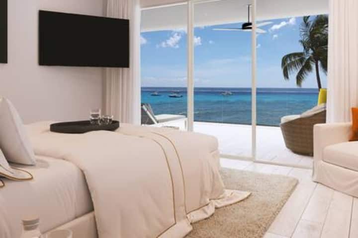 Hermoso dormitorio 2 con impresionantes vistas al mar.  La habitación cuenta con una cama tamaño king, aire acondicionado, ventilador de techo, televisor inteligente, caja fuerte de seguridad, vestidor, sistema de sonido, balcón compartido y baño privado de lujo.