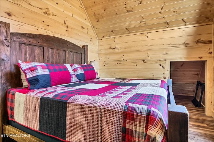 Spavaća soba | Gornja razina – veliki bračni krevet s uzglavljem od rustikalnog drveta i svodnim drvenim stropovima. Udobni popluni, noćne svjetiljke i mirno mjesto za opuštanje iznad velike prostorije. Skriveni kutak i spremište.