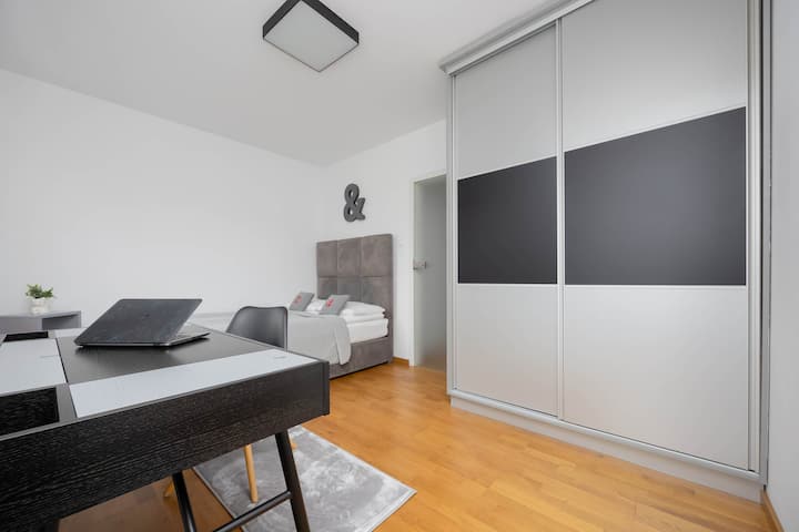 Un rincón de oficina en casa con un escritorio, una silla y un armario con puertas correderas con espejo.