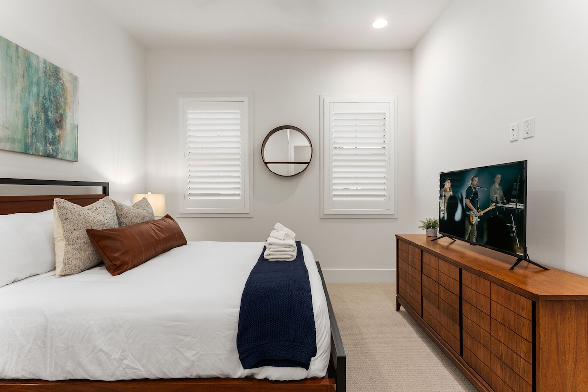 Cuarto dormitorio con cama tamaño queen, TV inteligente y vestidor.