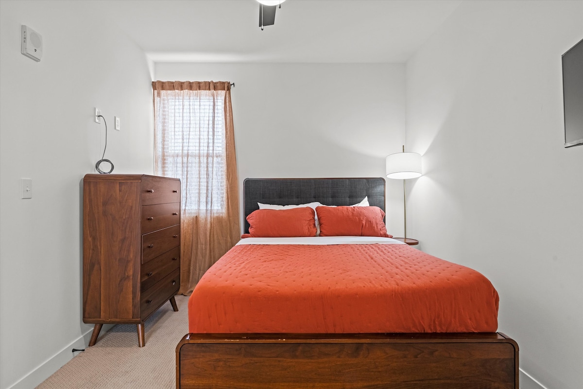 Gezellige slaapkamer met queensize bed, warme tinten en meubels uit het midden van de eeuw - perfect voor een goede nachtrust in North Kansas City.