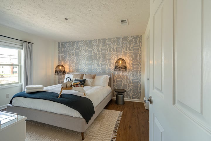 غرفة نوم رئيسية بسرير بحجم كبير وأثاث مصمم وتلفزيون ذكي وحمام داخلي.