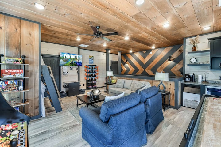 Рустикална соба за игра со голем телевизор, игри на табла и удобни седишта за семејна забава.