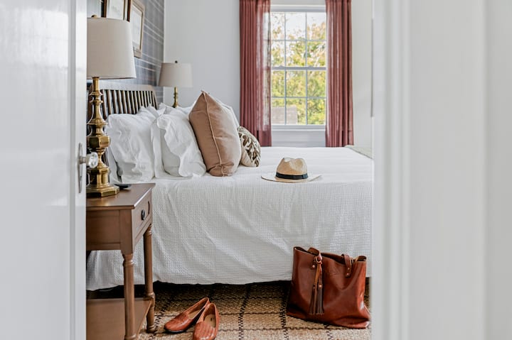 Krevat me shkumë memorieje "king" me shtroja hoteli, raft valixhesh, televizor inteligjent, tavolinë pune dhe karrige, stacion karikimi, perde të errëta