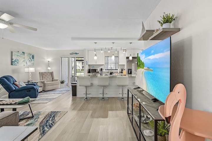 غرفة معيشة مشرقة ومفتوحة مع مقاعد مريحة والكثير من الضوء الطبيعي.