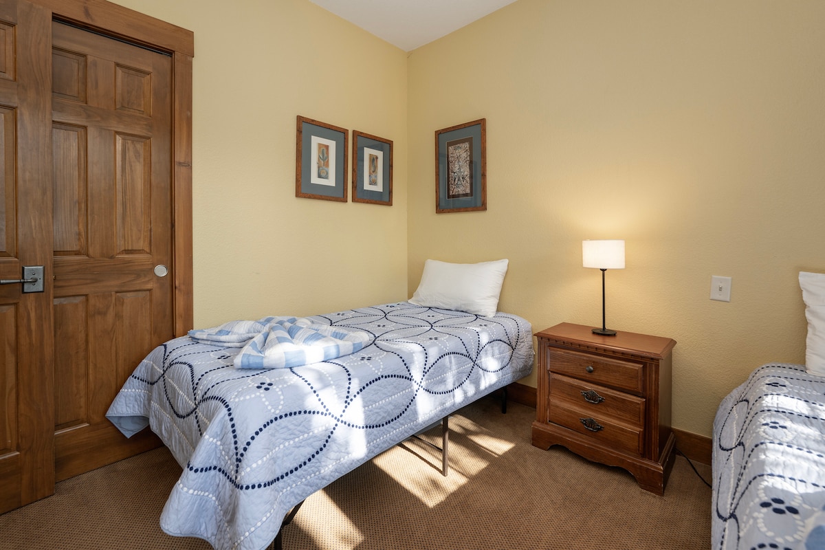 לשקוע בנוחות בחדר השינה הנעים שלכם עם שתי מיטות יחיד, תאורה חמימה ויצירות אמנות מוקפדות שיוצרות מקום מפלט שליו.