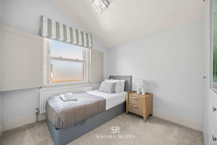 חלל מואר ושקט עם מיטת יחיד מסודרת ומצעים נקיים.