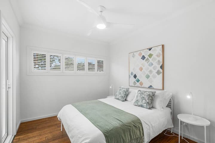 The third bedroom also features a queen bed, calming artwork, a ceiling fan and soft natural light through white shutters, offering an ideal place to sleep and unwind.
