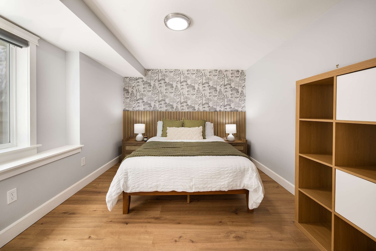 Спокойна стая с дървени акценти, тапети с листа и обилна естествена светлина.