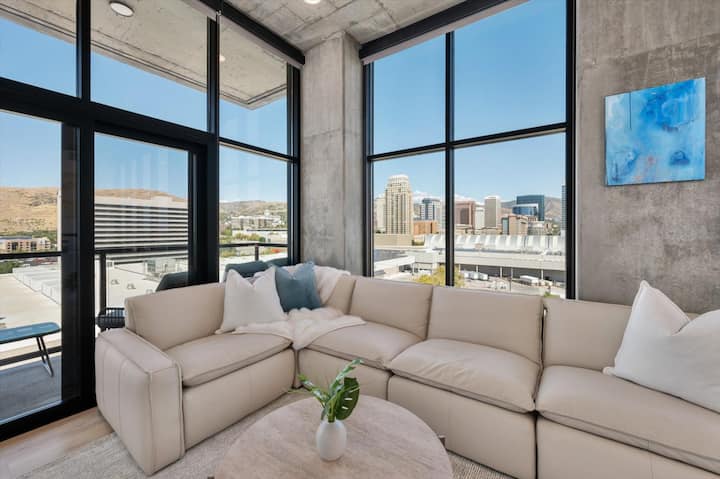 منطقة معيشة مصممة بشكل جميل. تلفزيون 65 بوصة، ومدفأة غاز، وأريكة جلدية مريحة واسعة مع إطلالة على مركز دلتا/ساحة الجاز خارج السطح.