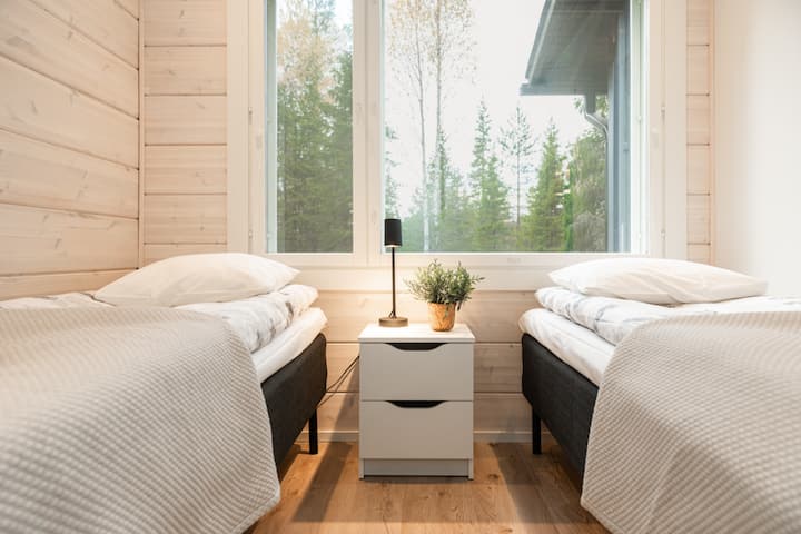 Светлата и спокойна стая за гости предлага две удобни единични легла и красива гледка към околната финландска гора.
